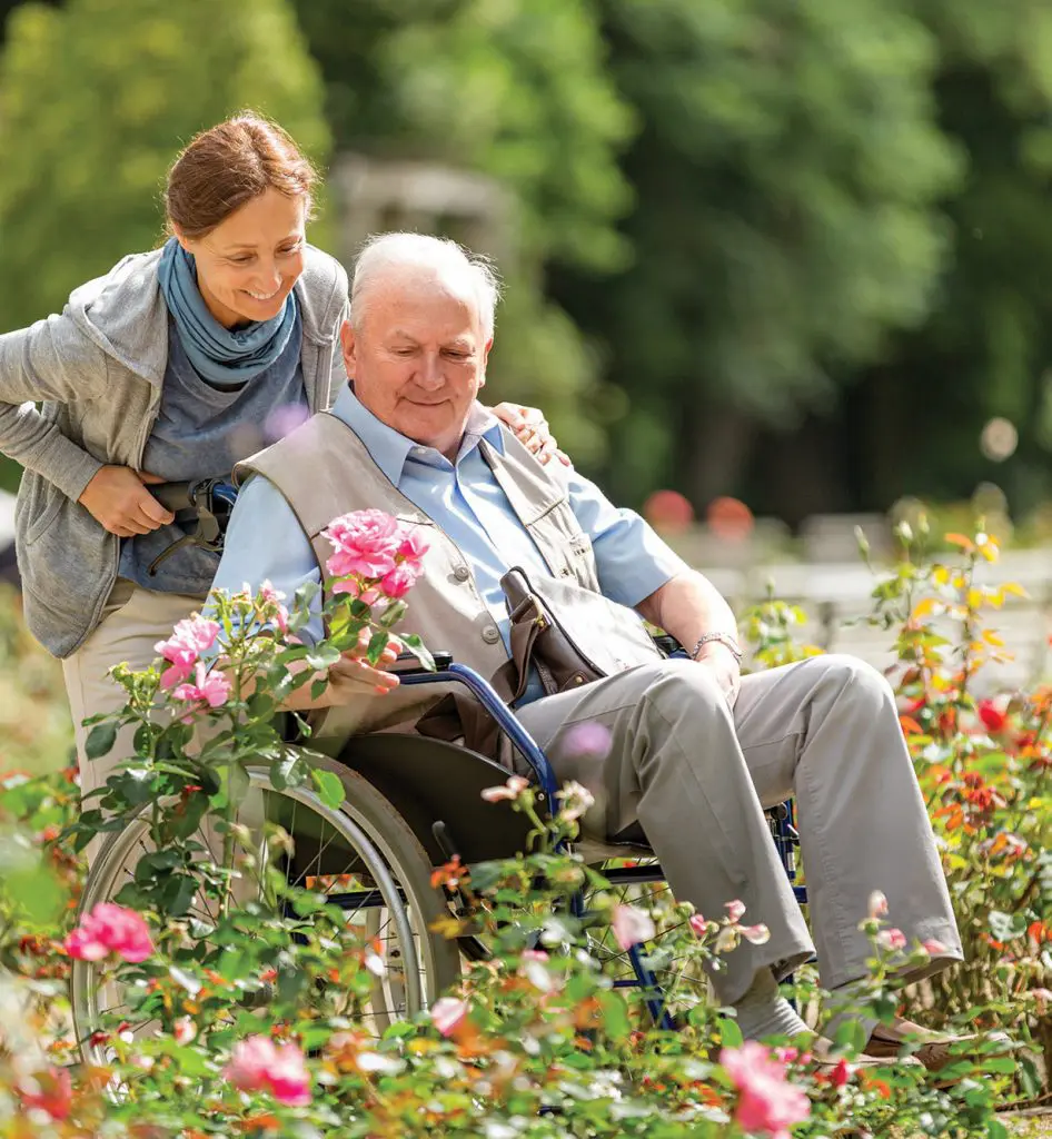 Senior Woman in Wheelchair with caregiver in a field of flowers Senior Woman in Wheelchair with caregiver in a field of flowers