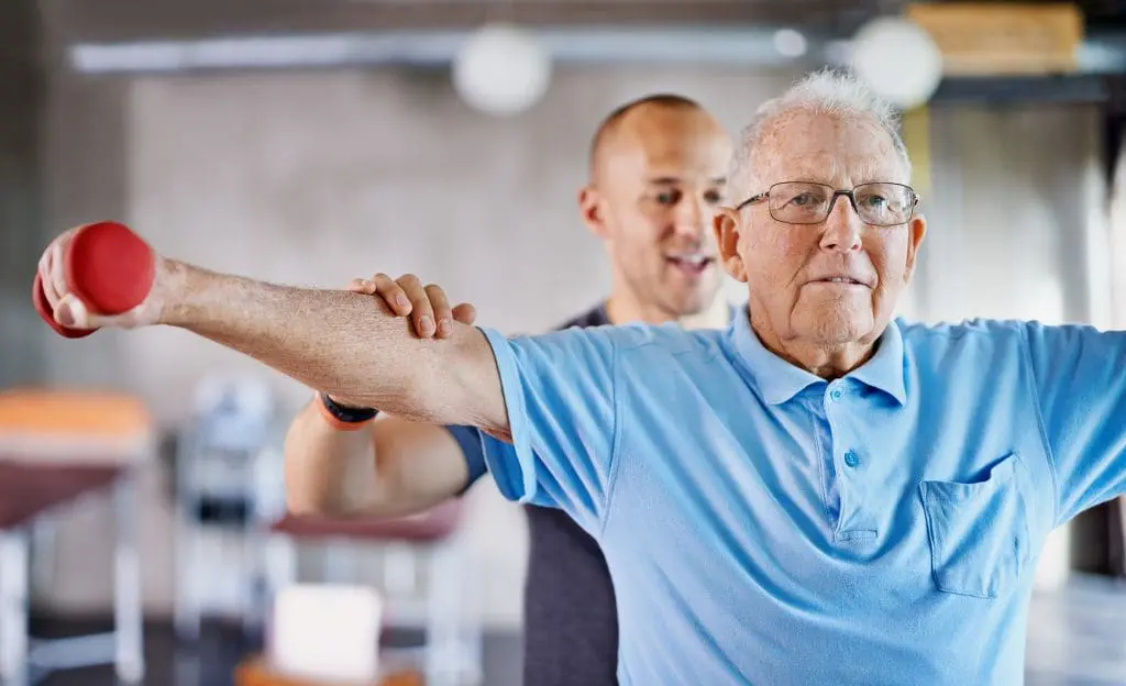 Rehabilitation patient lifting weights under the care of a trainer Rehabilitation patient lifting weights under the care of a trainer