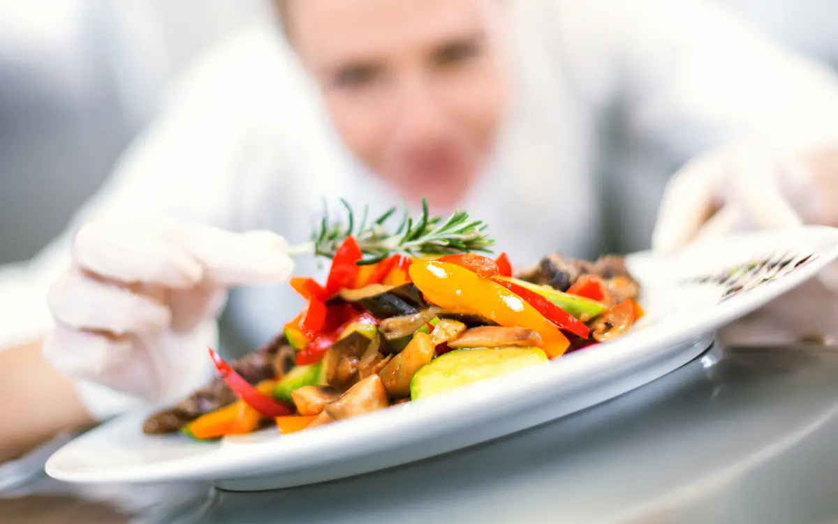 a chef styling a food plate for dinner at Peter Becker Community.