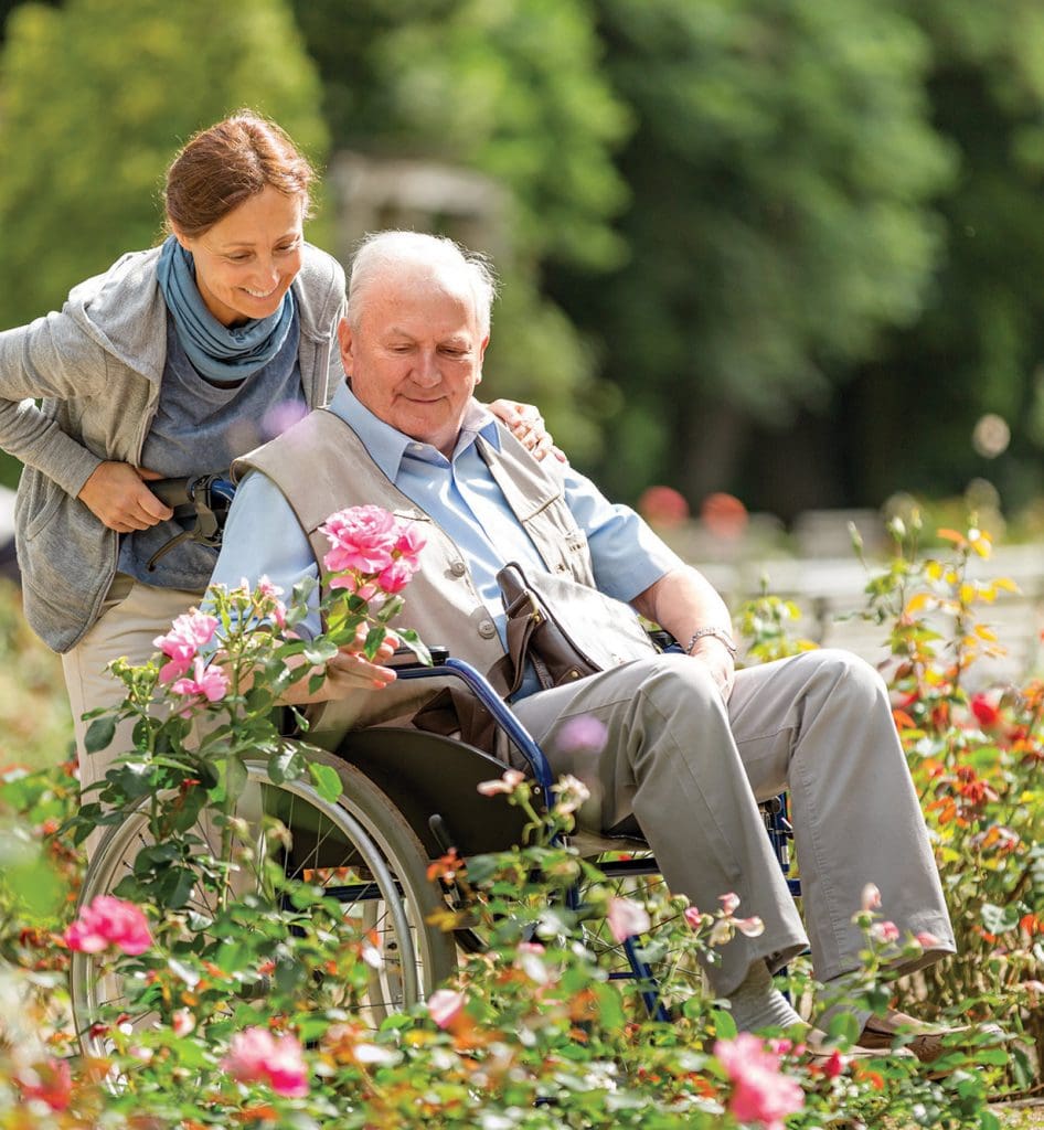 Senior Woman in Wheelchair with caregiver in a field of flowers