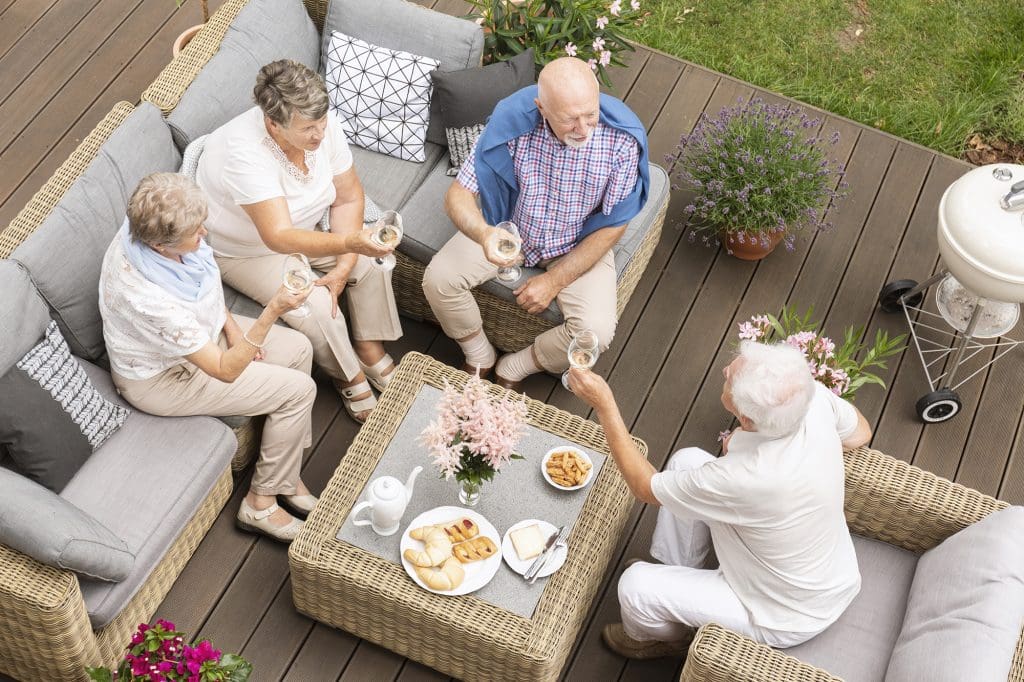Senior-aged friends toasting outside on the deck of a Cottages at Pondview residence