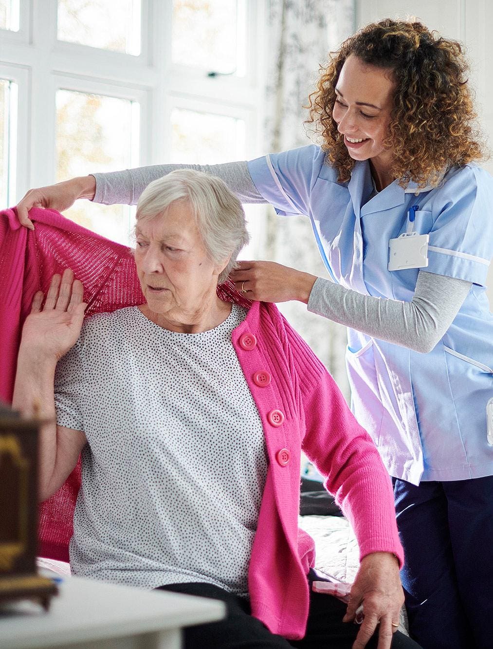 Caregiver assisting a resident with putting on their coat Caregiver assisting a resident with putting on their coat