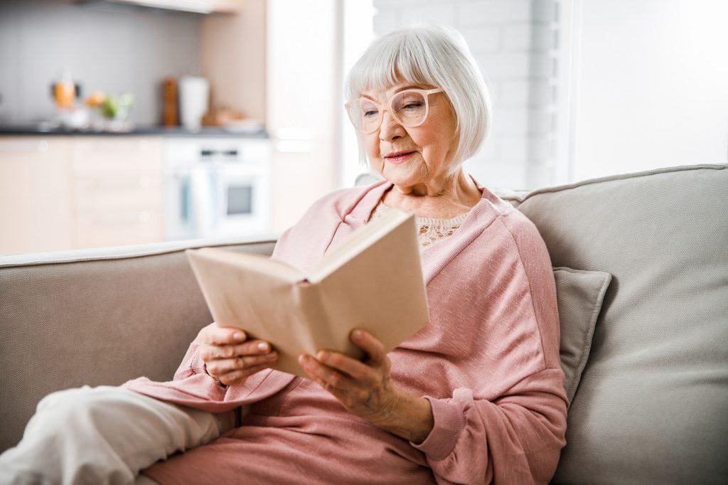 Senior woman in glasses reading book at home