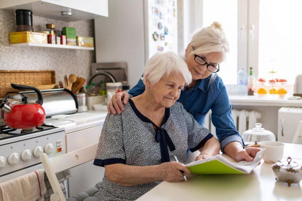 Mature woman helping elderly mother with paperwork Mature woman helping elderly mother with paperwork