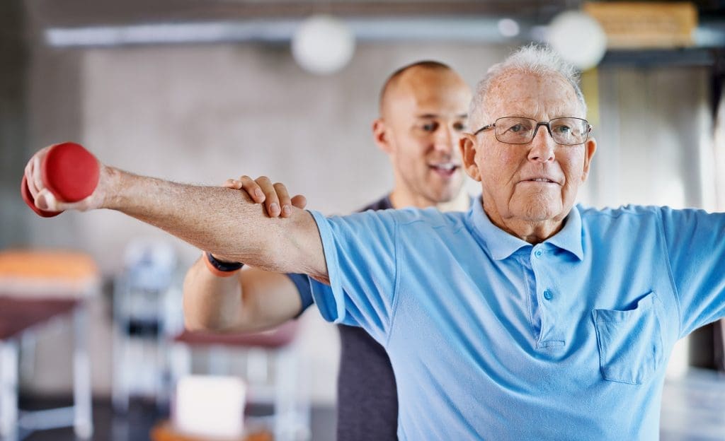 Rehabilitation patient lifting weights under the care of a trainer