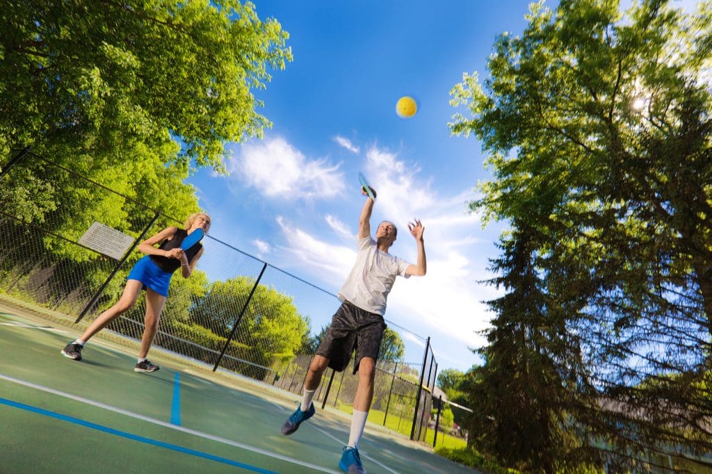 Older Adult Man and Woman Pickleball Player Playing Pickleball in Court Older Adult Man and Woman Pickleball Player Playing Pickleball in Court
