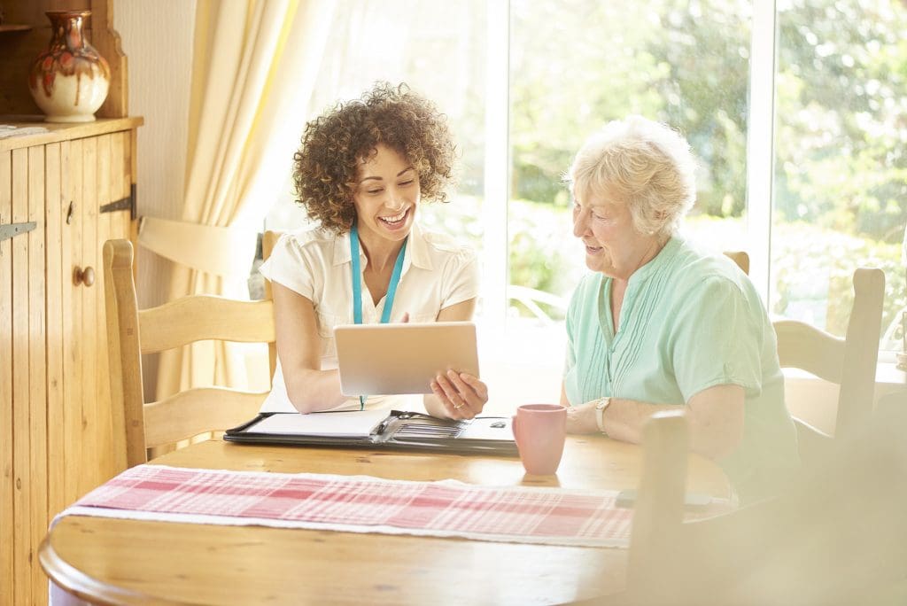 Caregiver Assisting Resident at Kitchen Table