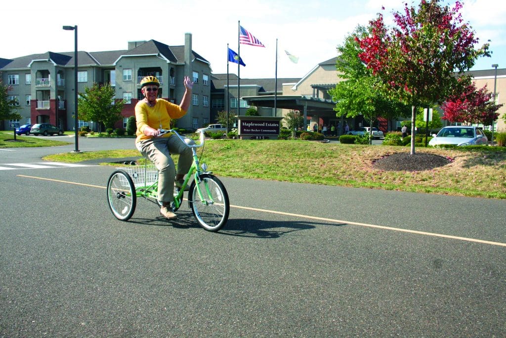 Senior aged woman riding a bike on Peter Becker Community campus