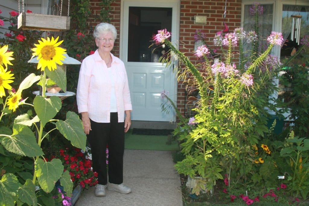 Peter Becker Community resident standing outside her home next to her flower garden