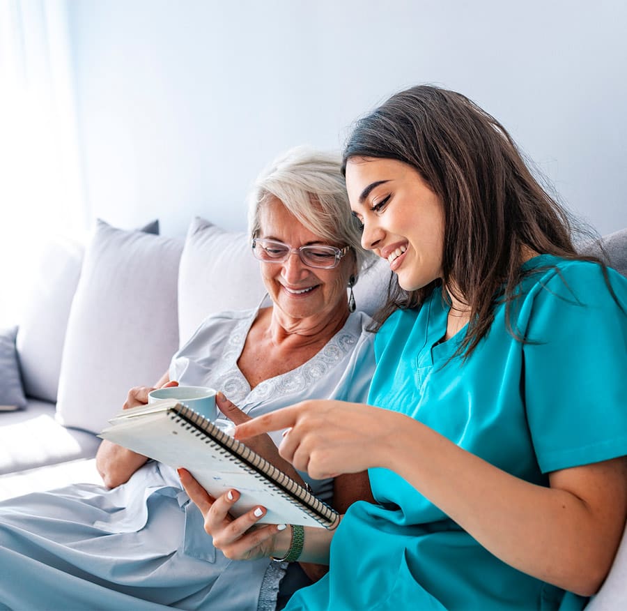 Older Adult Female with Caregiver on couch reviewing paperwork Older Adult Female with Caregiver on couch reviewing paperwork