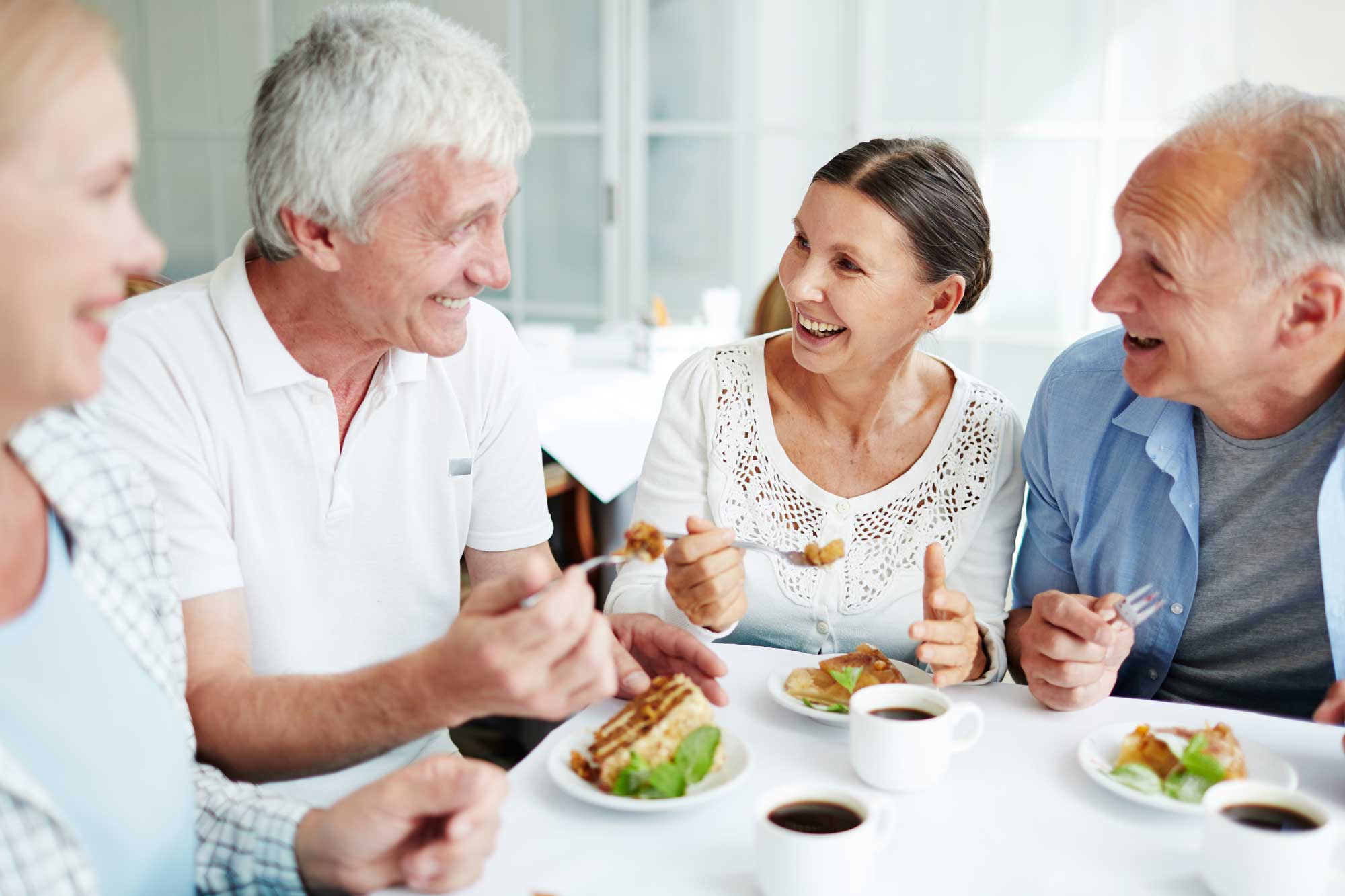 delish-dining Senior woman in glasses reading book at home