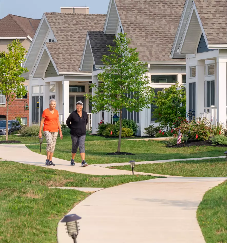 seniors-walking-neighborhood Caregiver handing a Senior-aged woman a cup of tea
