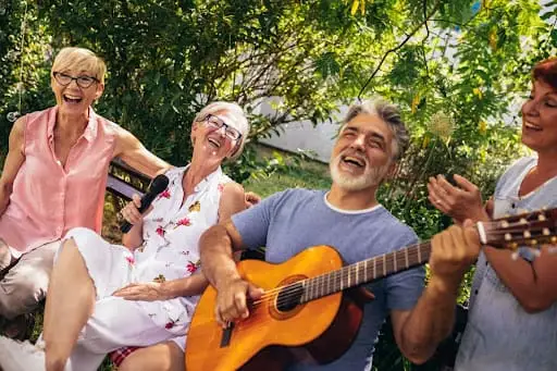 A group of elderly residents at Peter Becker Community singling along with an senior man play guitar as a part of exploring the benefits of creativity for seniors.